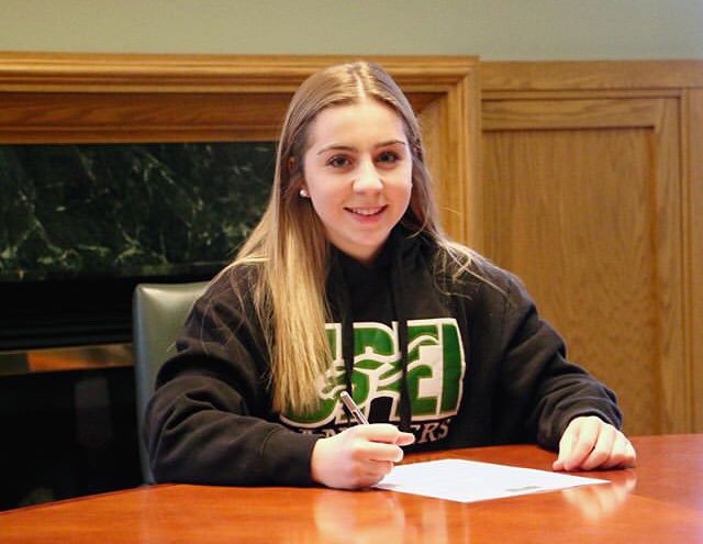 Tiah Scichilone A smiling student signs a piece of paper