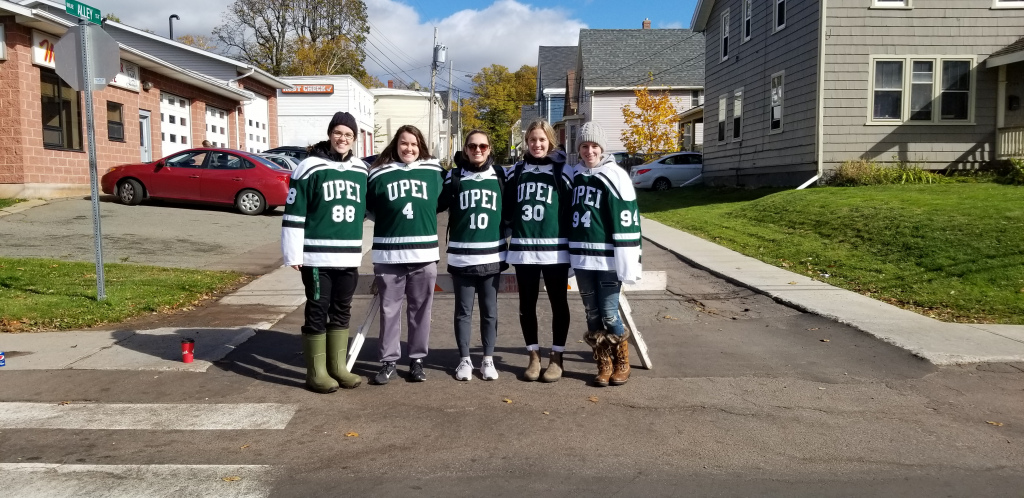 Members of the UPEI women’s hockey team Five female hockey players stand at an intersection in Charlottetown
