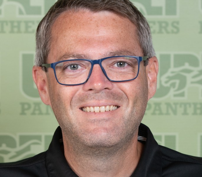 James Voye A smiling headshot of a man in glasses imposed over a a stylized UPEI Panthers background