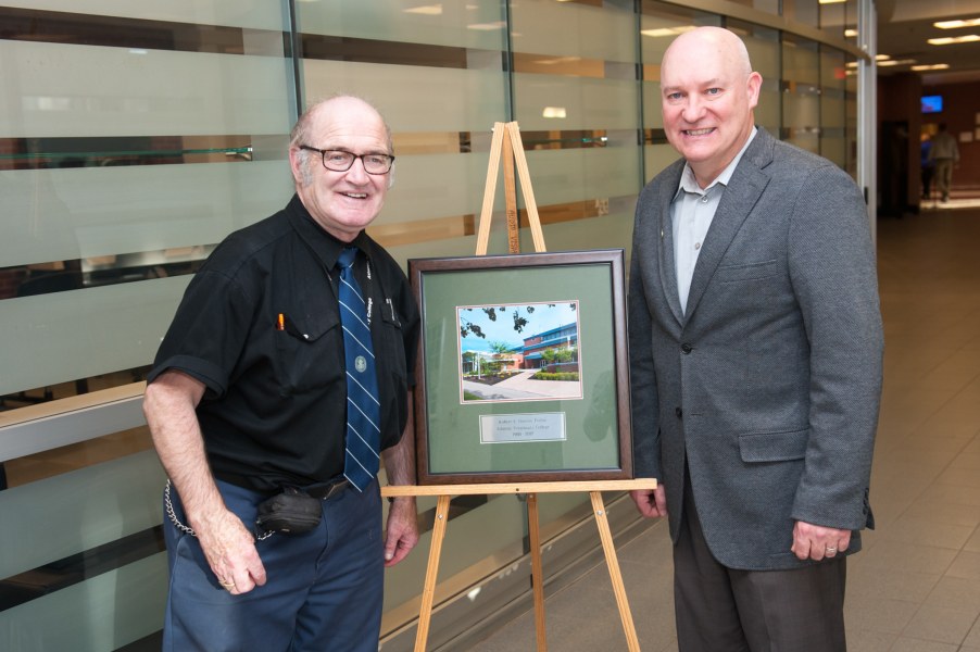 Upon his retirement, Robert Doiron, at left, received a framed photo from Dr. Greg Keefe, on behalf of the Atlantic Veterinary College Two men standing next a framed photo of AVC