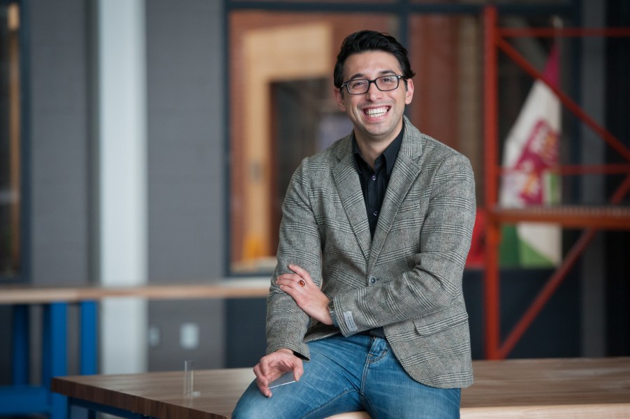Dr. Ali Ahmadi A smiling spectacled man in a casual blazer and jeans